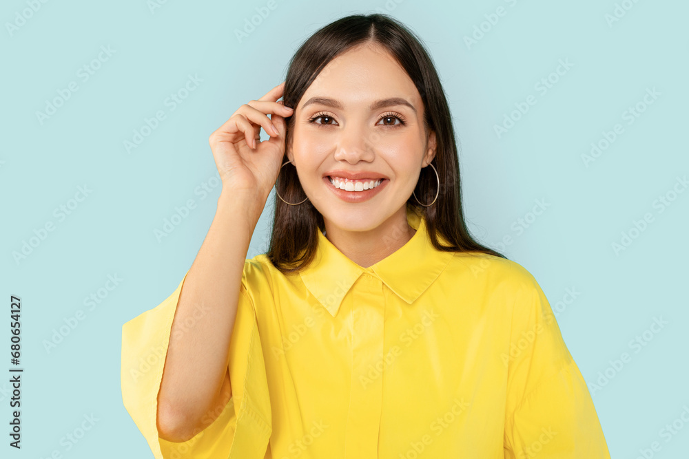 Studio portrait of cheerful young woman touching hair Studio portrait of cheerful young woman touching hair