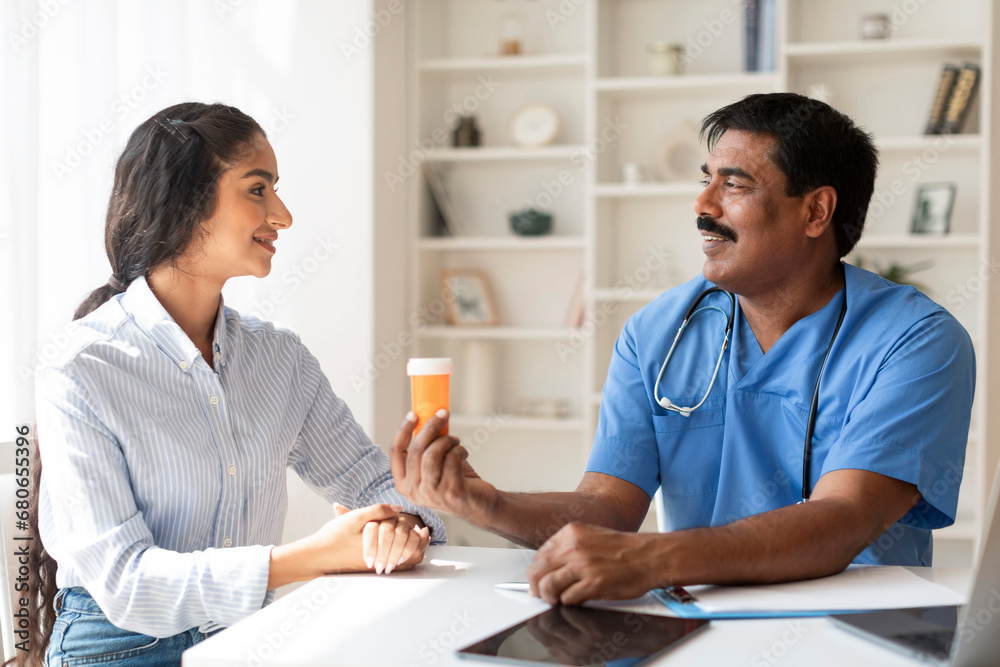 Mature Indian Doctor Man Giving Bottle With Pills To Smiling Female Patient Mature Indian Doctor Man Giving Bottle With Pills To Smiling Female Patient