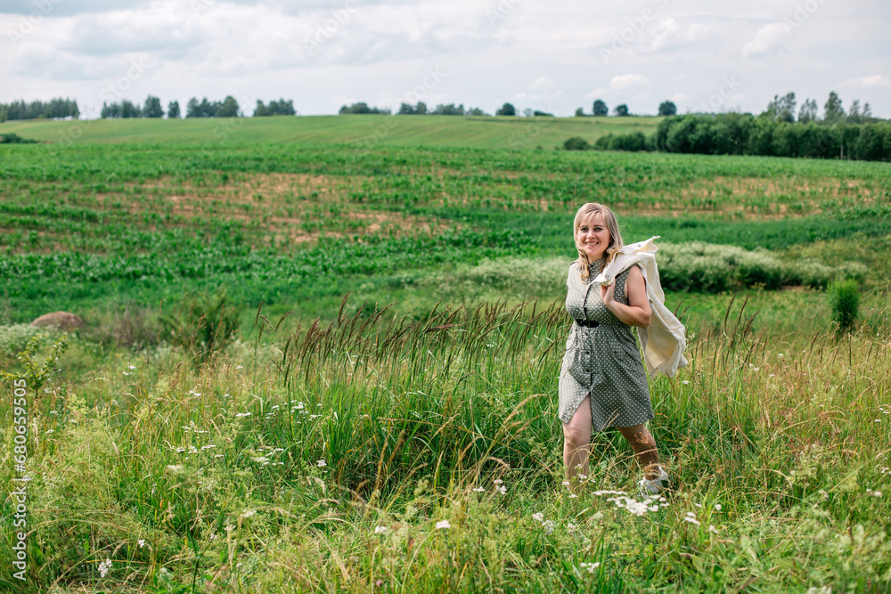 Beautiful woman walking in a summer field with a jacket over her shoulder