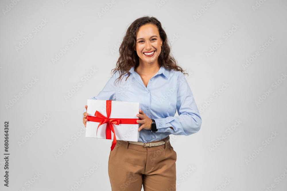Positive young european businesswoman in formal wear hold box with gift, enjoy birthday, surprise on anniversary Positive young european businesswoman in formal wear hold box with gift, enjoy birthday, surprise on anniversary