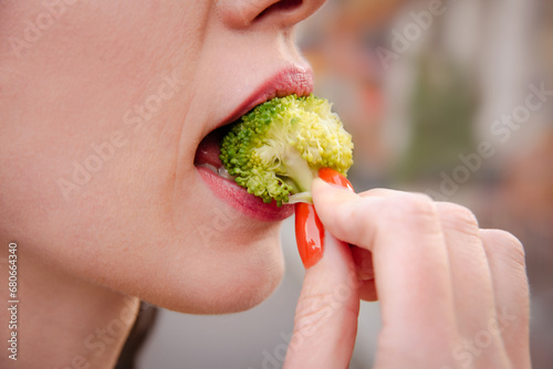 woman eat healthy green broccoli for healthy lunch on street outdoors