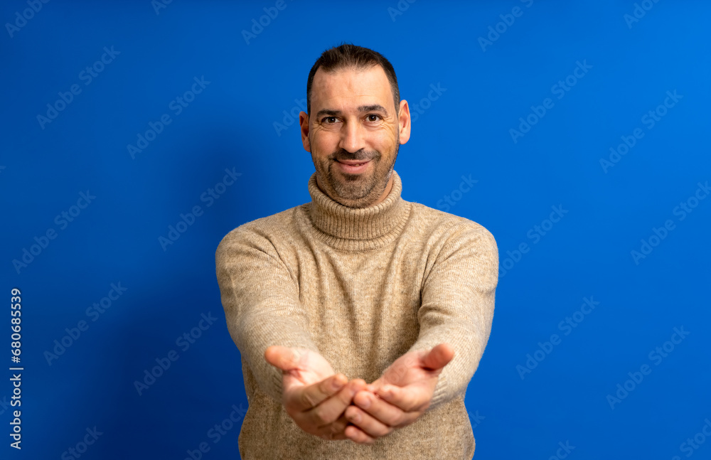 Handsome hispanic man about 40 standing over blue background smiling cheerful offering palms giving assistance and acceptance Handsome hispanic man about 40 standing over blue background smiling cheerful offering palms giving assistance and acceptance