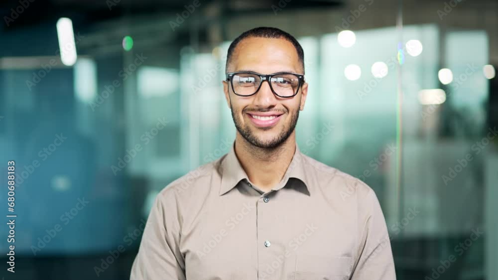 Portrait of a young man in glasses and shirt smiling and looking at the camera while standing in a modern office. Handsome mixed race man posing with crossed arms and a friendly expression on his face Portrait of a young man in glasses and shirt smiling and looking at the camera while standing in a modern office. Handsome mixed race man posing with crossed arms and a friendly expression on his face