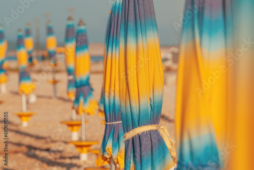 Folded colorful beach umbrella parasols on Adriatic sea coast in sunny summer morning, holiday and vacation background with copy space photo