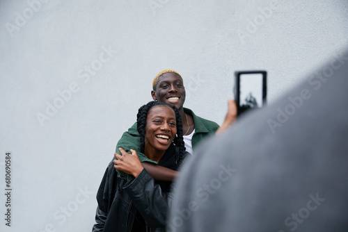 Stylish black friends with cool natural hair pose together for photo taken by their friend on a digital camera