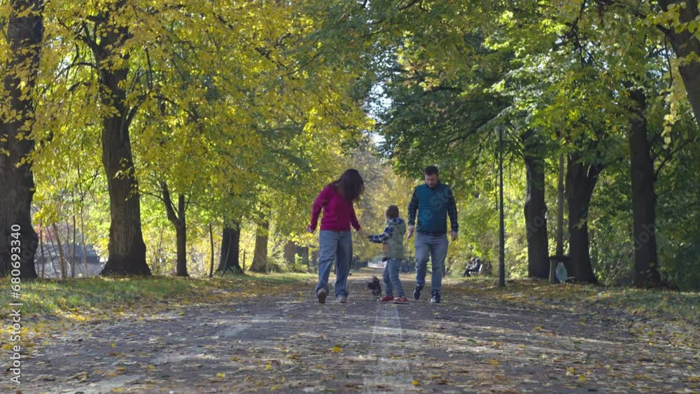 Happy family walking on yellow leaves in autumn park. Cheerful and smiling parents and children take care of pets in nature together. High quality 4k footage Happy family walking on yellow leaves in autumn park. Cheerful and smiling parents and children take care of pets in nature together. High quality 4k footage