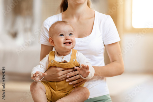 Smiling cute infant baby boy sitting in mother arms