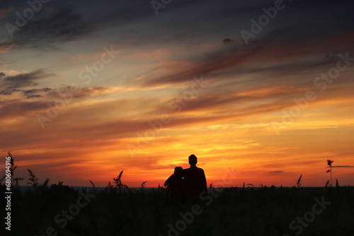 Mother and adult son silhouette in the summer meadow on a sunset background. Sunset 10 August 2023 year, msk time.