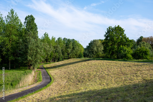 Green hills and a bending cycling trail at the dam of the River Scheldt, Dendermonde, Belgium