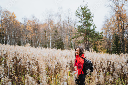 Girl traveling alone with backpack in the forest, hiking in autumn esu, young beautiful woman trekking in nature.