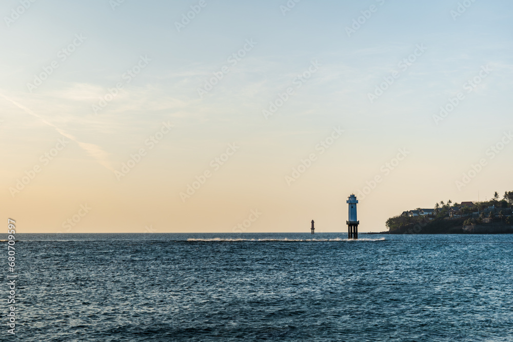 Beautiful sunset at the sea with an isolated lighthouse standing off beach coastline Beautiful sunset at the sea with an isolated lighthouse standing off beach coastline