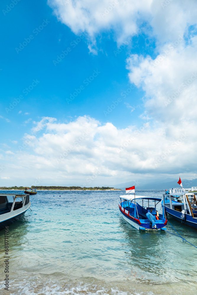 Tropical sandy beach with turquoise ocean and boats at Gili Meno, one of the Gili islands in Lombok, Indonesia