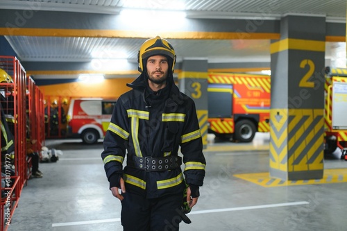 Fireman wearing protective uniform standing in fire department at fire station