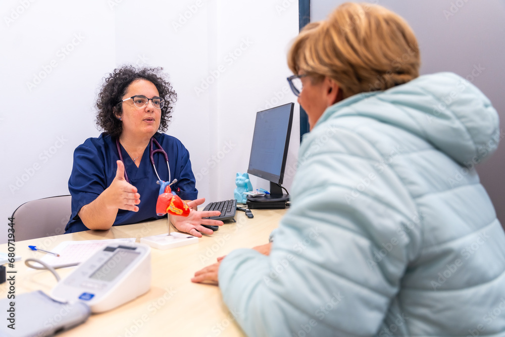 Female cardiologist doctor at the cardiology clinic talking to a client Female cardiologist doctor at the cardiology clinic talking to a client