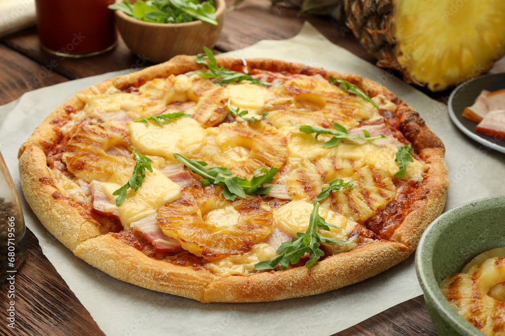 Delicious pineapple pizza with arugula on wooden table, closeup