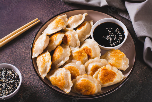 Crispy fried dumplings with soy sauce and sesame seeds on a plate on the table