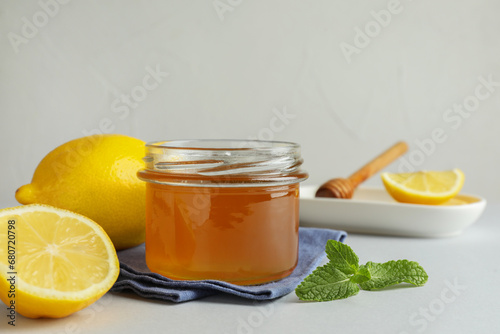 Sweet honey and fresh lemons on white table, space for text