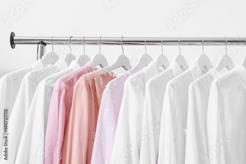 Rack with different stylish shirts near white wall, closeup. Organizing clothes © New Africa