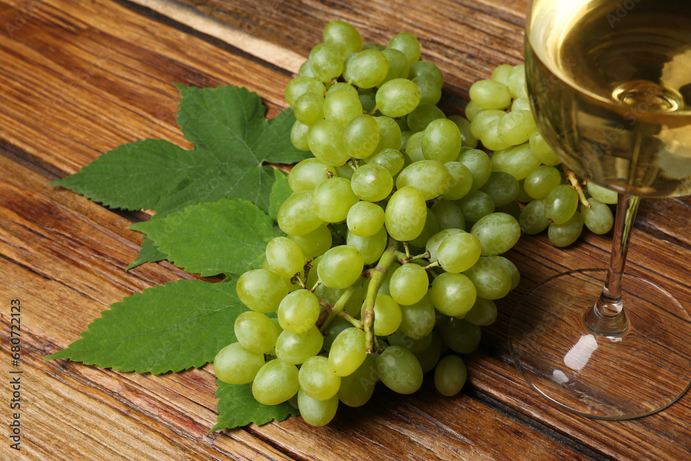 Delicious fresh green grapes, leaves and glass of wine on wooden table Delicious fresh green grapes, leaves and glass of wine on wooden table