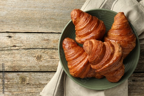 Delicious fresh croissants on wooden table, top view. Space for text