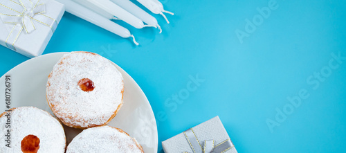 Symbols of Jewish religious holiday Hanukkah. Traditional dessert donuts sufganiyot on blue background.