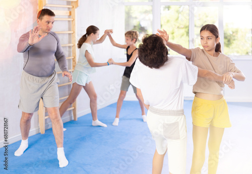 Boy and girl practicing self-defense techniques in group at gym