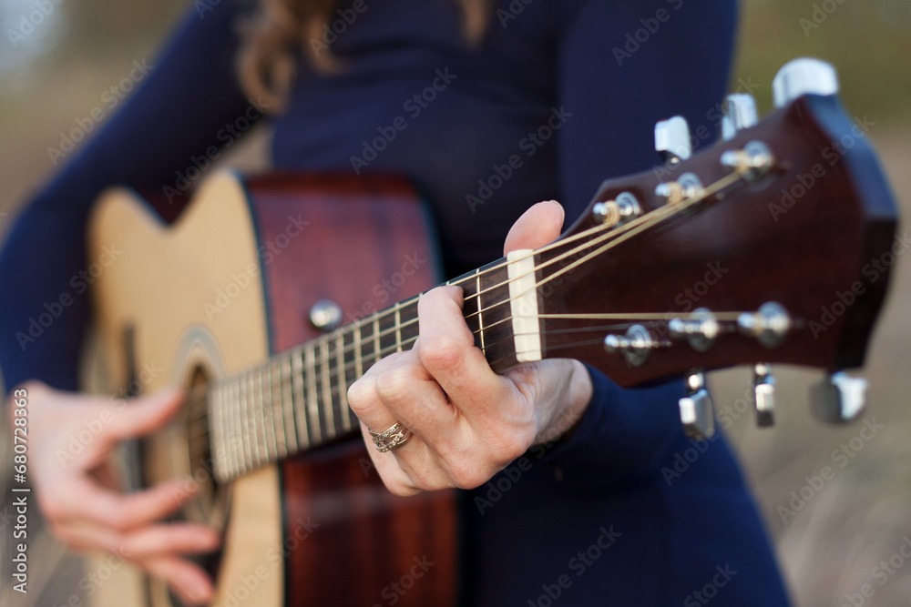 Close-up of woman's hands playing an acoustic guitar. Outdoor leisure, creative evening, warm autumn, sunset. Romantic mood. Selective Focus