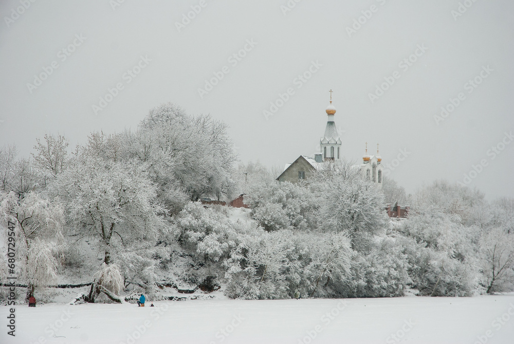 Winter landscape on a frozen lake. White snow on the trees and a church on the shore. Winter landscape on a frozen lake. White snow on the trees and a church on the shore.