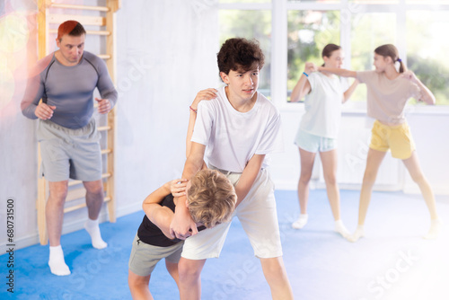 Two boys training self-defense techniques in group in studio