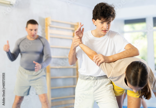 Girls and boys learns to do power grip with trainer during a self-defense lesson in the gym