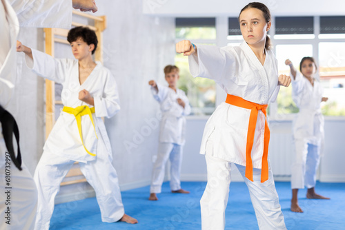 Children athletes starting position and studying and repeating sequence of punches and painful techniques in karate kata technique. Oriental martial arts, training and obtaining black belt