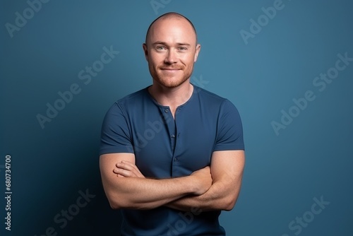 Portrait of a handsome bald man with crossed arms over blue background