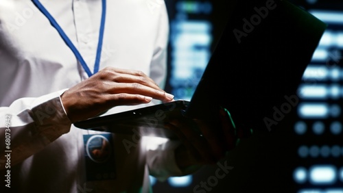 Admin using laptop to survey supercomputers providing vast computing resources and storage, enabling artificial intelligence to process massive datasets for training and inference, close up photo