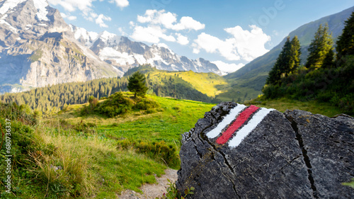 White and red trail waymark in a hiking path in the Swiss Alps with blurred background - trail signs in the Swiss Alps photo