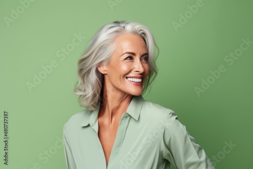 Cheerful mature woman looking at camera and smiling while standing against green background