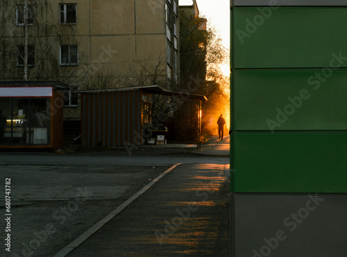 Fototapeta Naklejka Na Ścianę i Meble -  Silhouette of a man walking down the street in the light of the evening sun