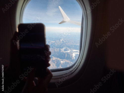 View from an airplane window of a mountain area and left wing, warm sunny day. Travel and tourism view. Flying to holiday destination point. Scene through illuminator. High viewpoint.