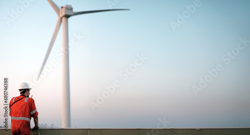 Offshore technician. Seafarer. Seaman. Navigator. A Man in a Boiler Suit is Standing In Front Of The Wind Generator. Seafarer In front of the Wind Generator. Wind Farm Construction Site.