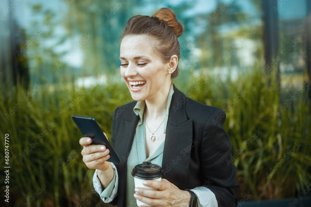 smiling woman worker near office building using phone