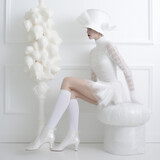 Photo de mode d'une femme habillée avec une robe blanche et des bas blancs, décor épuré, voile et nacre,