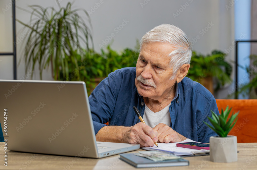 Senior man accounting payments calculating monthly expenses bank bills analyzing paperwork at home apartment indoors. Elderly mature grandfather freelancer working online remote job on laptop at table Senior man accounting payments calculating monthly expenses bank bills analyzing paperwork at home apartment indoors. Elderly mature grandfather freelancer working online remote job on laptop at table