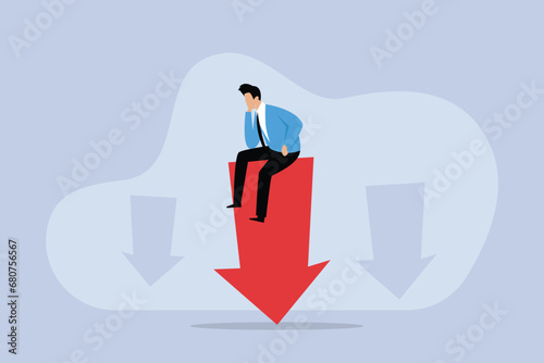 Stressed businessman sitting on a down arrow