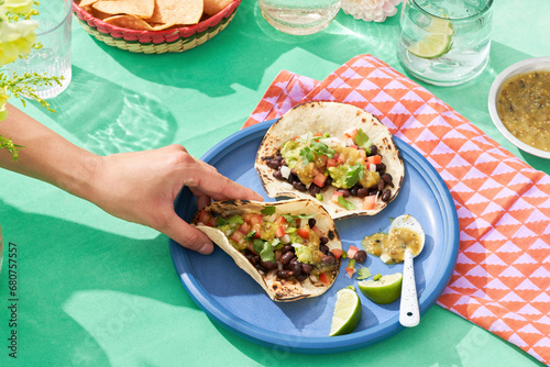 Obraz na plátně Vividly colorful Mexican fare with hand grasping taco