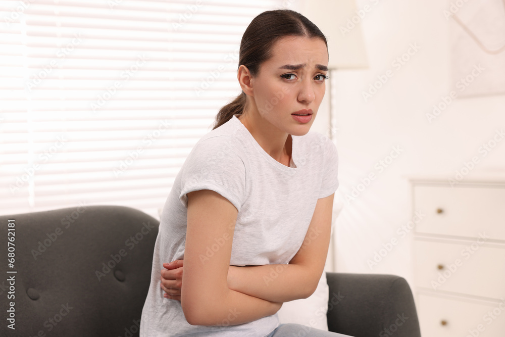 Woman suffering from abdominal pain on sofa at home. Unhealthy stomach Woman suffering from abdominal pain on sofa at home. Unhealthy stomach