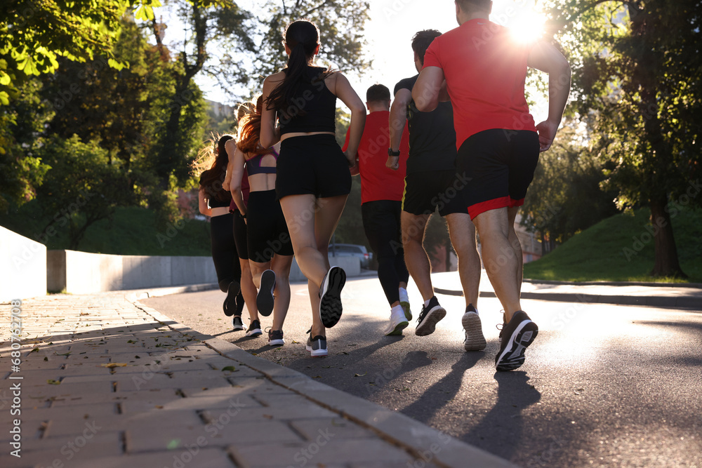 Obraz premium Group of people running outdoors on sunny day, back view