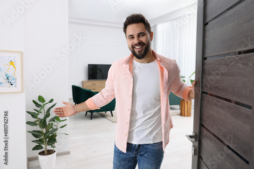 Happy man welcoming near door. Invitation to come indoors