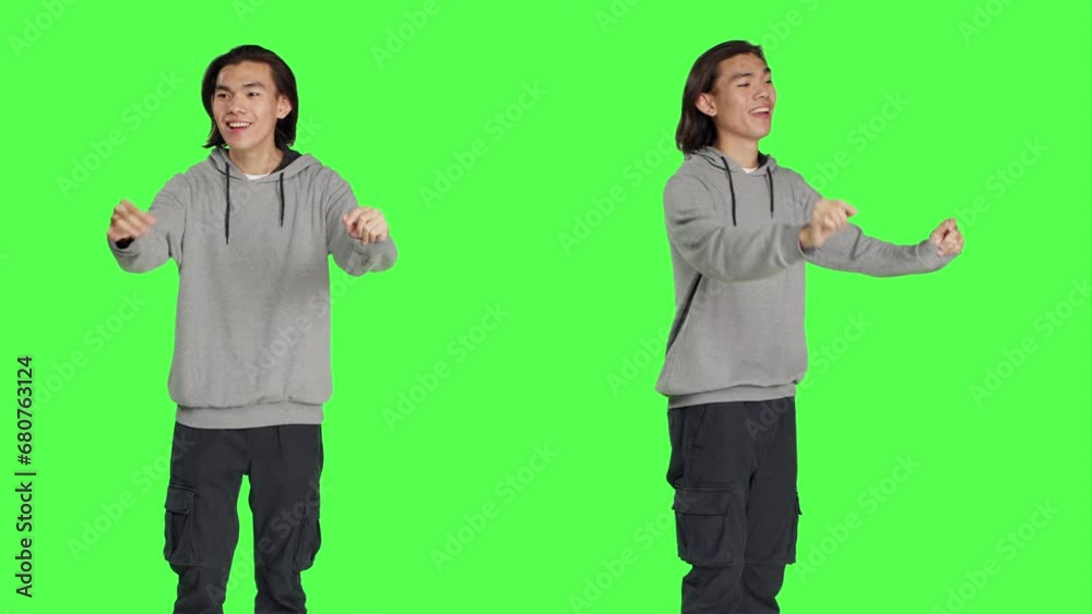 Asian guy acting as choir conductor for musical show, moving hands like a bandmaster director over greenscreen backdrop. Male model conducting band to sing, smiling choirmaster. Asian guy acting as choir conductor for musical show, moving hands like a bandmaster director over greenscreen backdrop. Male model conducting band to sing, smiling choirmaster.