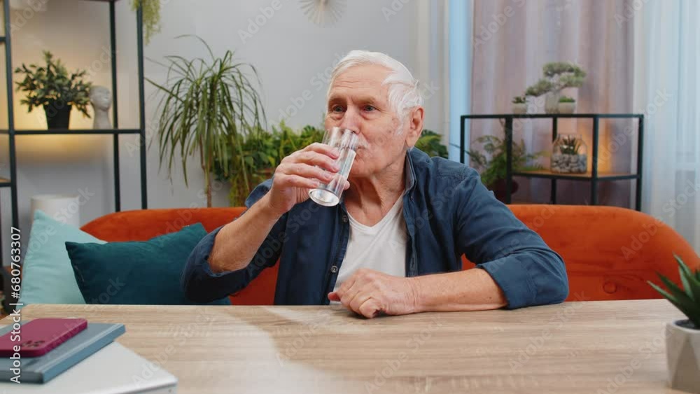 Thirsty senior man hold glass of natural filtered aqua make sips