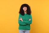 Happy young woman in stylish green sweater on yellow background