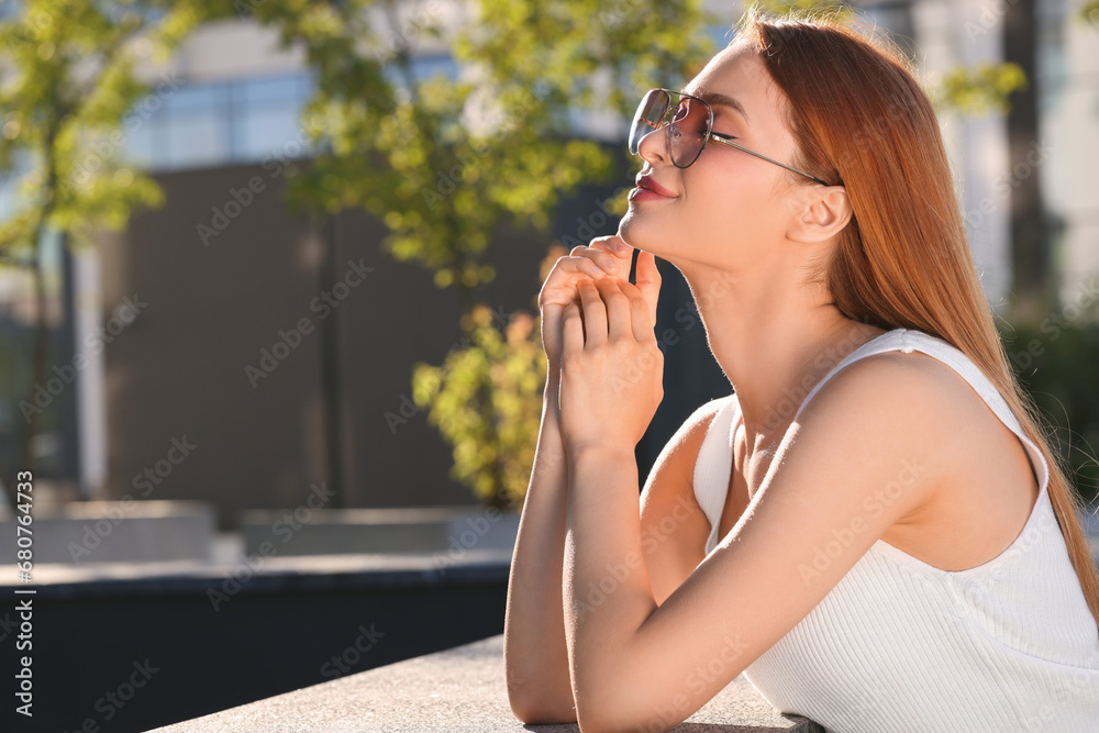 Beautiful woman in sunglasses outdoors, space for text